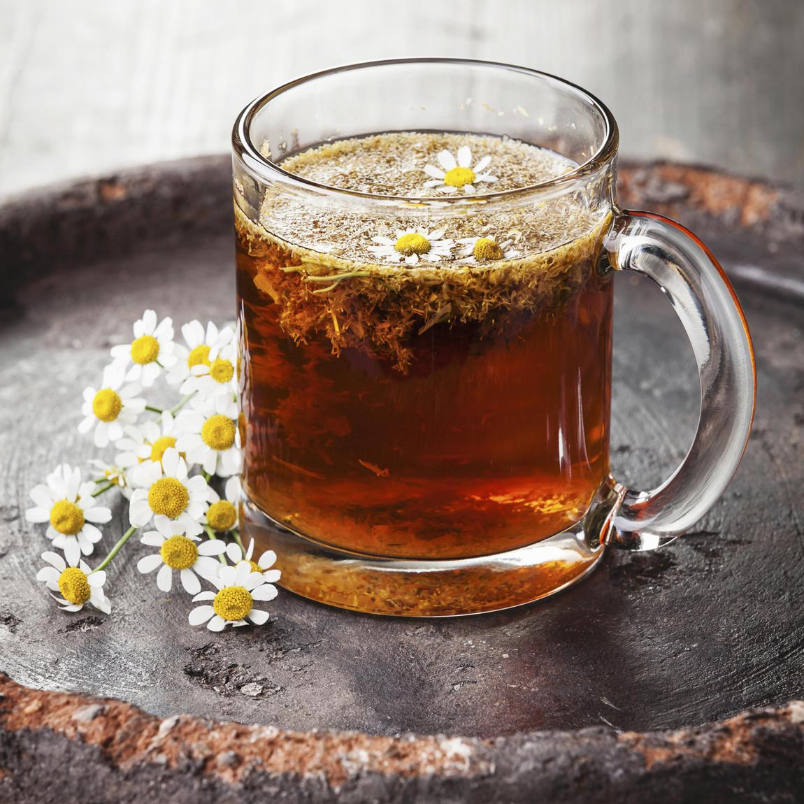 Chamomile tea with chamomile flowers on dark background