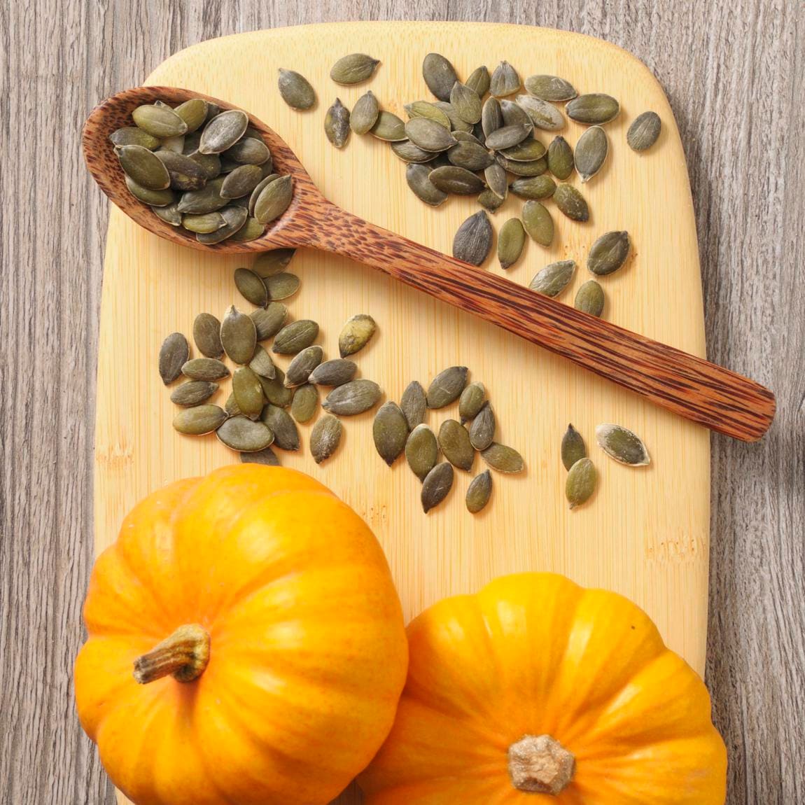 Pumpkin seeds and mini pumpkins on a chopping board