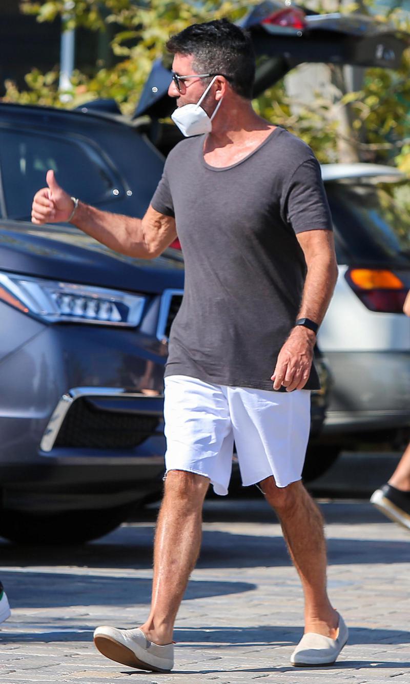 Simon Cowell looks happy walking after breaking his back